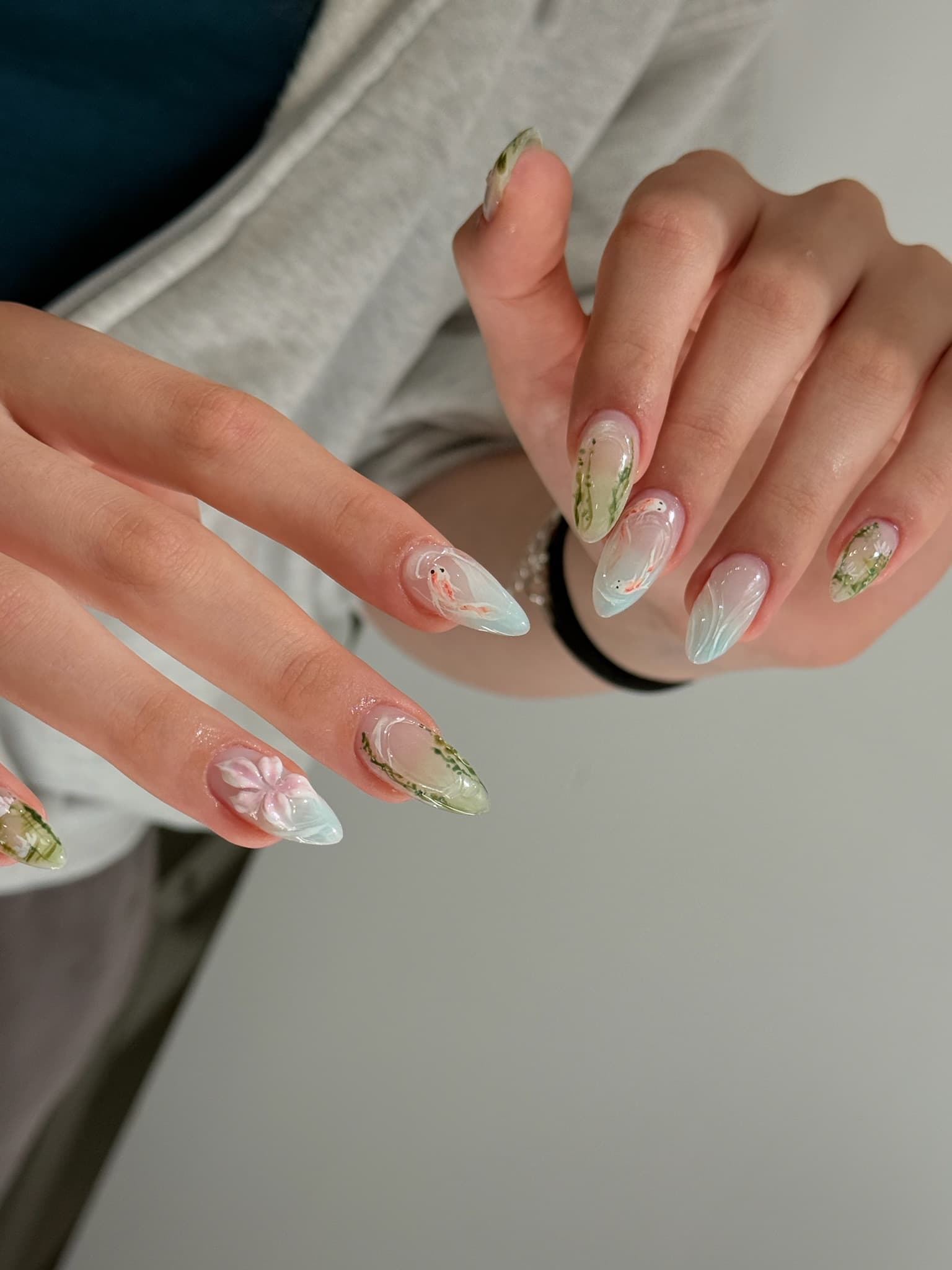 Hand-painted koi pond gel nails — almond set with koi fish, pond greenery and a 3D flower accent